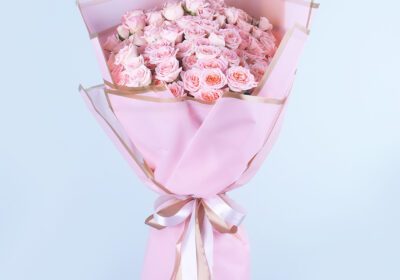 A bouquet of Pink flowers Warper in a pink and gold paper tied with a whote ribbon.