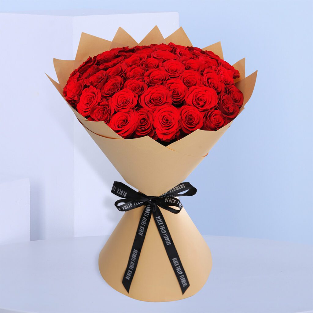 Large red roses are elegeantlly arranged in a big bouquet.