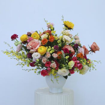 A colorful vase arrangement with roses, ranunculus, and wildflowers.