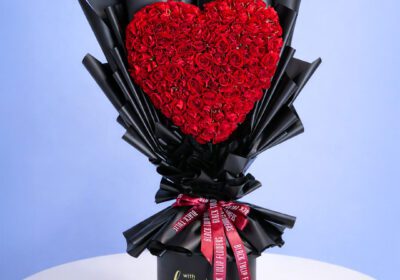 A bouquet of vibrant red roses arranged in a sleek black vase.