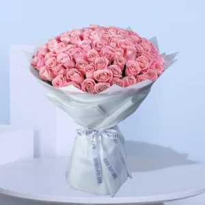 A large bouquet of pink roses wrapped in white paper.