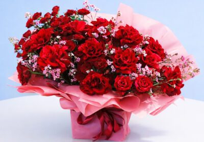 Bouquet featuring red roses and pink flower in blush pink wrapping.
