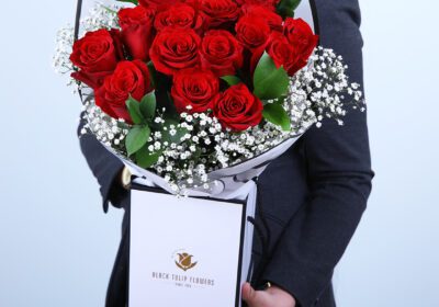 A girl holding a bag of premium long-stem red roses arranged for gifting.