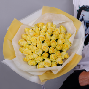 Bouquet of yellow roses wrapped in yellow and white paper.
