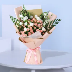 The bouquet features a mix of white and light pink flowers, including small roses, with green leaves interspersed throughout