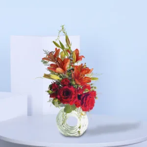 A vibrant floral arrangement is displayed in a unique, round glass vase with a central opening