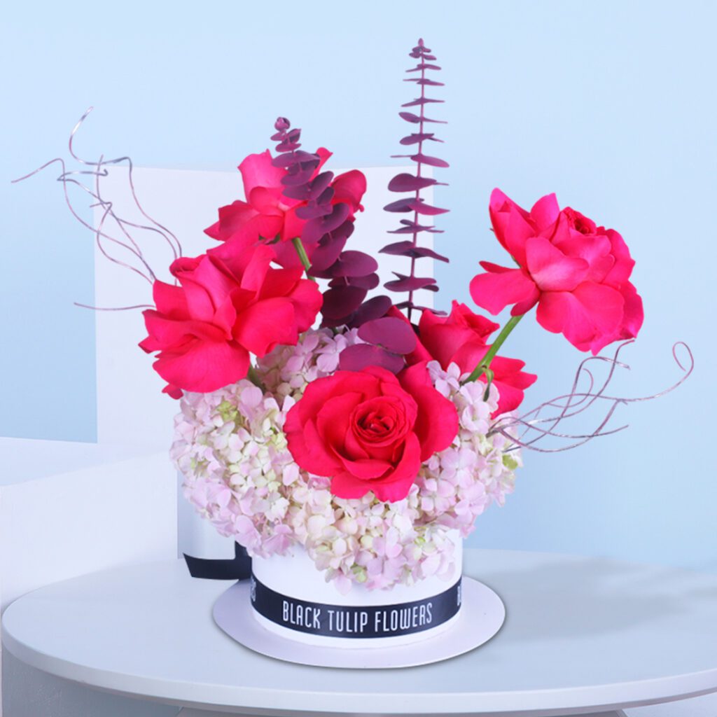 Pink rose arrangement with baby’s breath and foliage in a stylish floral box.