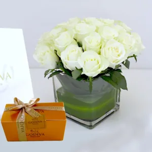 a charming arrangement of pristine white roses in a modern, square glass vase