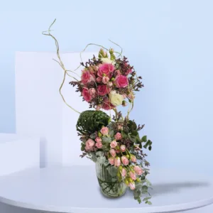 A floral arrangement called "Twilight Rose Cascade" featuring garden roses, peonies, and protea in a baroque style. The arrangement is composed of two main sections: an upper spherical bouquet of pink and white roses with dark filler flowers, and a lower cascading arrangement of smaller pink roses and greenery.