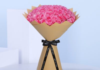 A bouquet of pink roses arranged in a rustic brown paper bag.