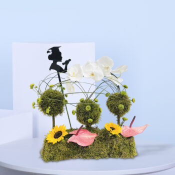 Graduation-themed flower arrangement with orchids, sunflowers, moss balls, anthuriums, and a graduate silhouette decoration.