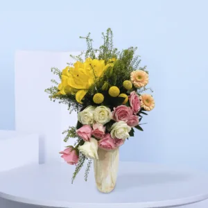 A cheerful arrangement of golden lilies, blush pink and ivory roses, peach gerberas, and fresh greenery in a chic marble vase—ideal for gifting or décor.