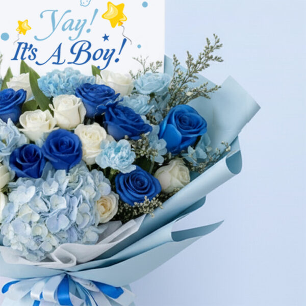 Blue baby boy bouquet with roses, hydrangeas, and other blooms and “It’s a Boy” card.