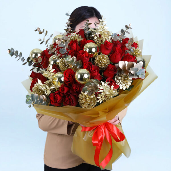 Christmas bouquet with red roses, gold pinecones, golden ornaments, and with festive wrapping