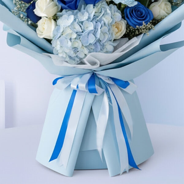 Blue baby boy bouquet with roses, hydrangeas, and other blooms and “It’s a Boy” card.