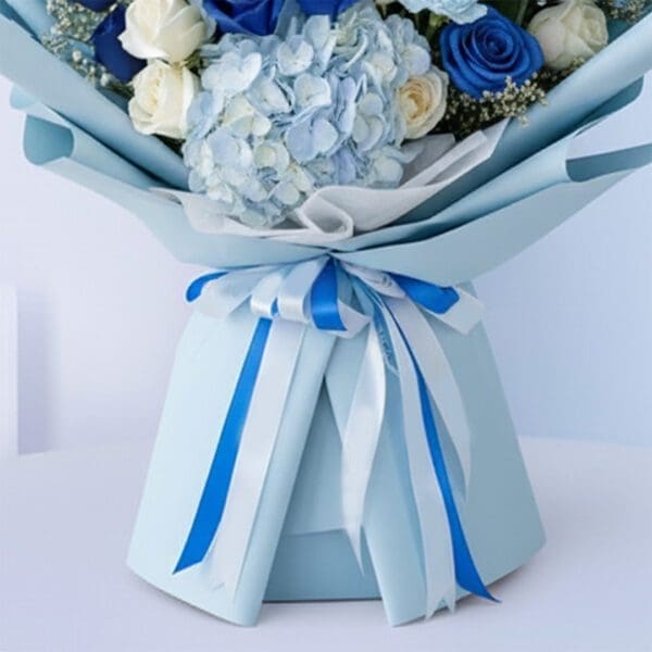 05 Blue baby boy bouquet with roses, hydrangeas, and other blooms and “It’s a Boy” card.