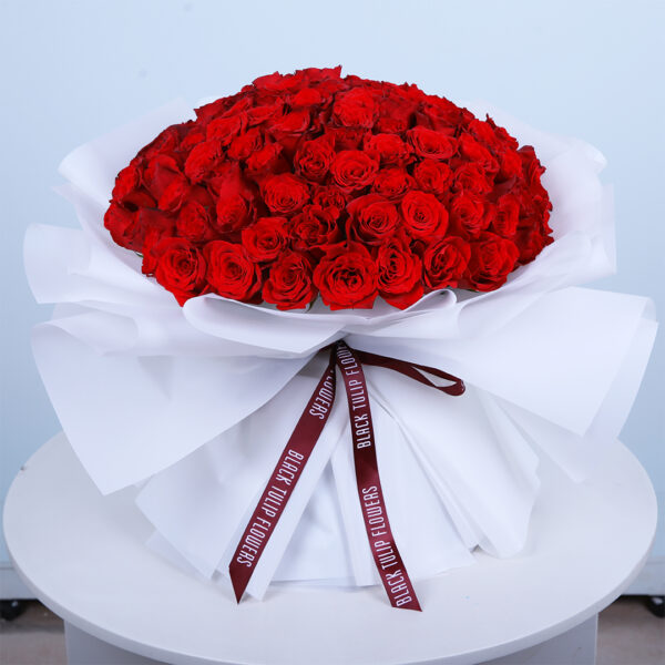 101-red-roses-bouquet._02 Bouquet featuring hand-tied 101 long-stemmed red roses in white wrap, finished with branded ribbon.