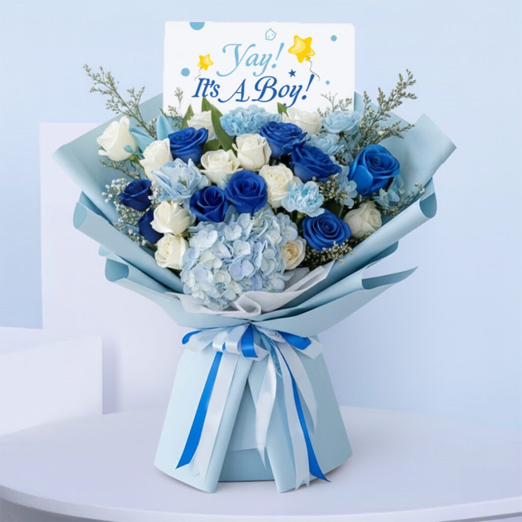 Blue baby boy bouquet with roses, hydrangeas, and other blooms and “It’s a Boy” card.