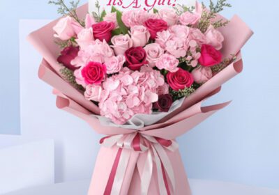 Pink baby girl bouquet with roses, hydrangeas, carnations, and “It’s a Girl” card.