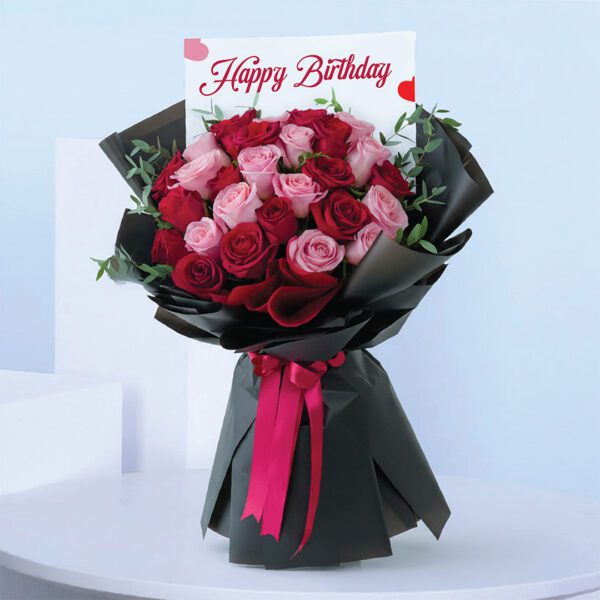 birthday-roses-bouquet. Birthday bouquet with pink and red roses wrapped in black paper and bright ribbon.