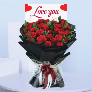 Bouquet featuring hand-tied red roses in elegant black wrap with lace bow, finished with a “Love You” card