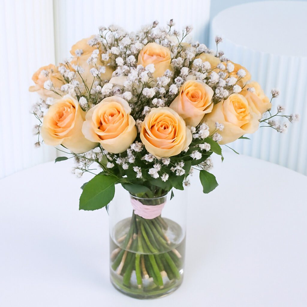 20 peach roses with baby’s breath in a clear glass vase.