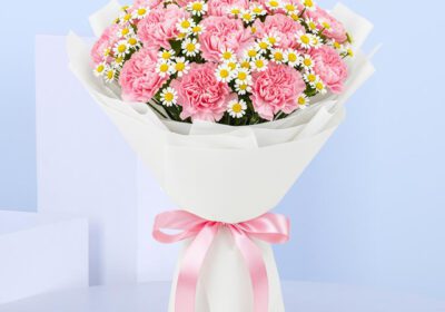 Bouquet of hand-tied light pink carnations & tanacetum in white wrap, finished with a pink satin ribbon.