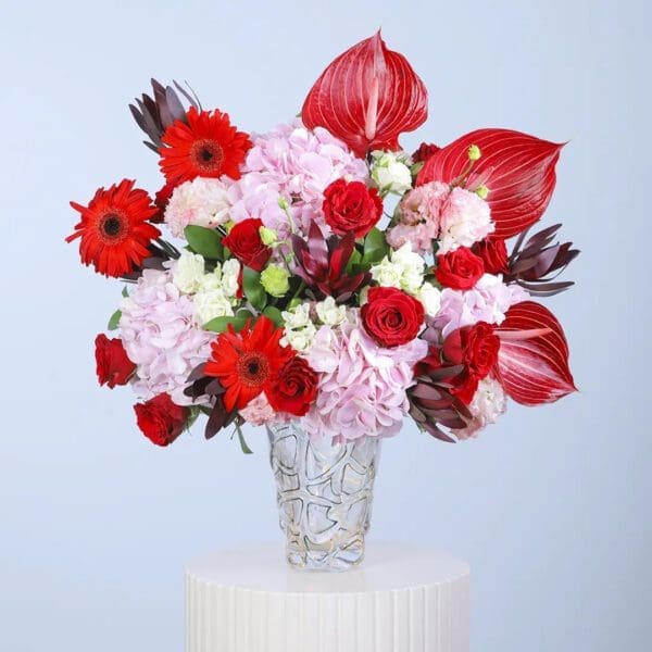 red-anthurium-pink-hydrangea-rose-vase Pink hydrangeas, red anthuriums, red roses, red gerberas and white filler blooms in a clear glass vase arrangement