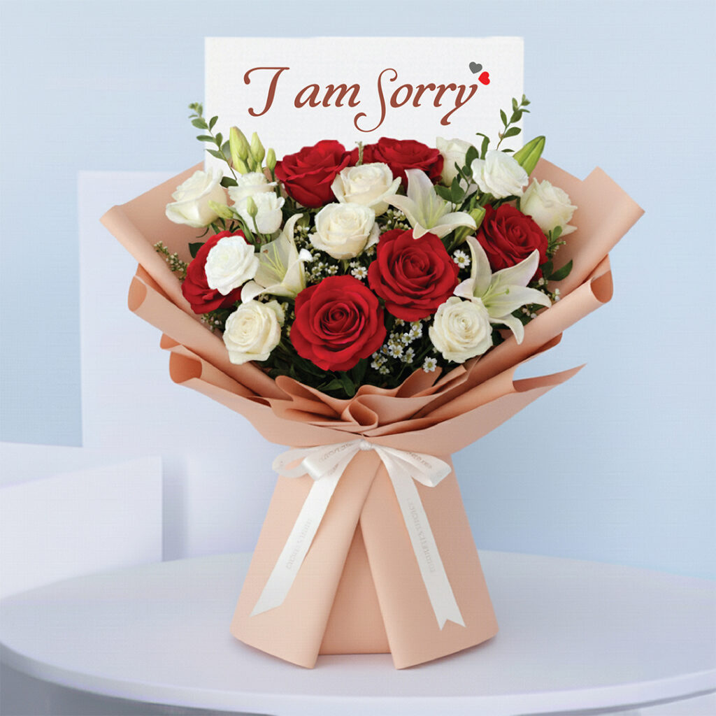 Bouquet featuring hand-tied red roses, white roses & lilies in peach wrap, finished with an “I am Sorry” card.