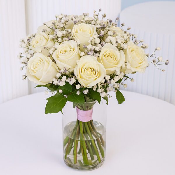 20 white roses with baby’s breath in a clear glass vase.