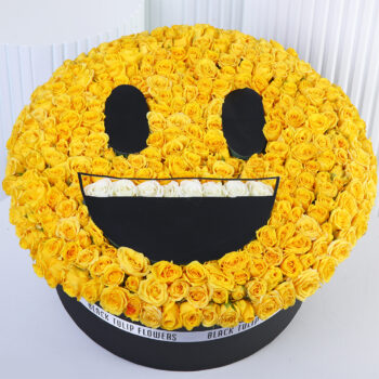 Yellow spray roses arranged in a smiling emoji-style floral box with white rose detailing.