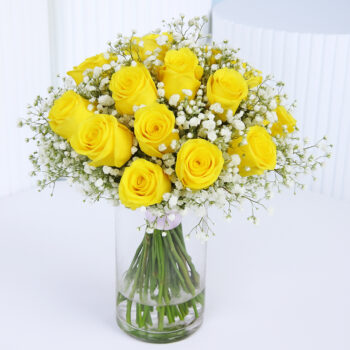 20 Sunny yellow roses styled with delicate baby’s breath in a clear glass vase