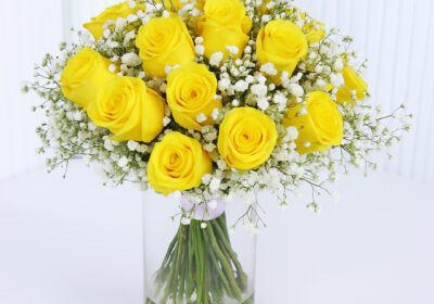 20 Sunny yellow roses styled with delicate baby’s breath in a clear glass vase