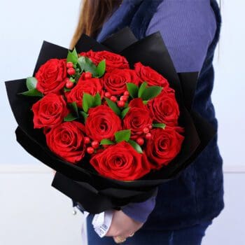12 red roses with hypericum berries and ruscus greens bouquet in elegant black wrapping
