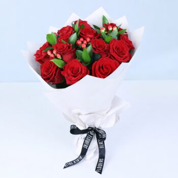 12 red roses with hypericum berries and ruscus greens in elegant white wrapping,