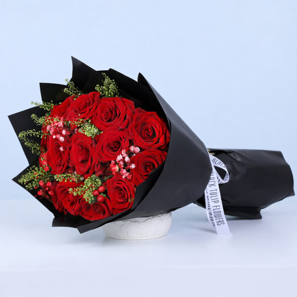 15 red rose bouquet with delicate filler flowers and green foliage in black wrap