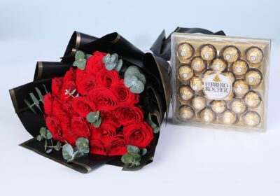 A gift combo of 20 red roses and 10 eucalyptus stems in black wrap, finished with a ribbon, and Ferrero Rocher chocolate gift box.