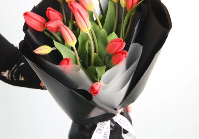 A bouquet of 20 red tulips, wrapped in black with a ribbon.