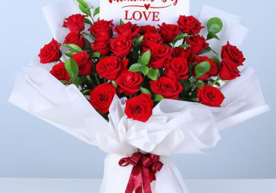 25 red roses bouquet wrapped in white paper with ribbon.
