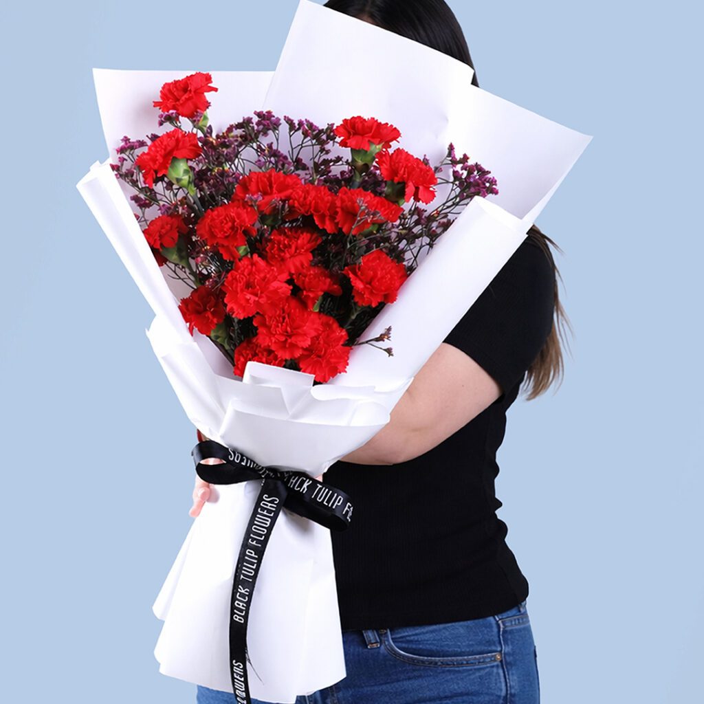 20 red carnations and wax flowers in premium white wrap