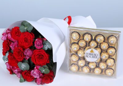 A bouquet of red and pink roses, and eucalyptus in white wrapping style, finished with a ribbon, paired with a Ferrero Rocher chocolate gift box.