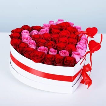 Bouquet featuring red roses and pink roses in a white heart-shaped gift box with a red ribbon