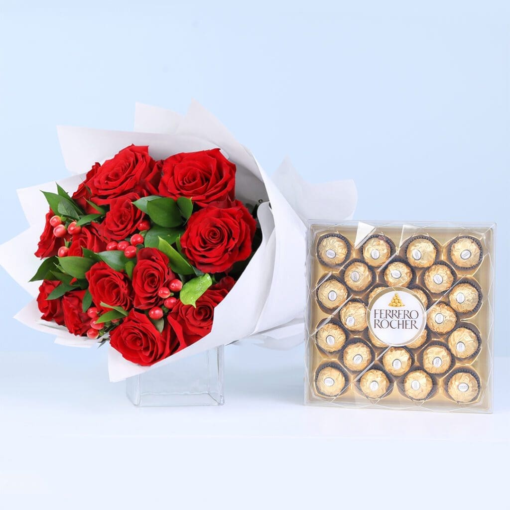 12 red roses with hypericum berries and ruscus greens in elegant white wrapping, finished with a Ferrero Rocher chocolate box