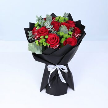 Red roses with eucalyptus leaves and green filler flowers in elegant black wrap