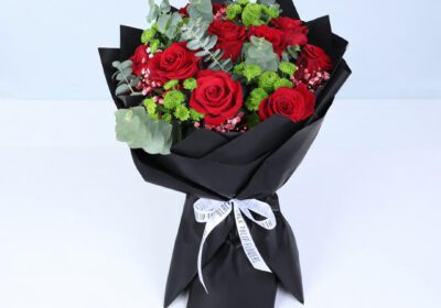 Red roses with eucalyptus leaves and green filler flowers in elegant black wrap