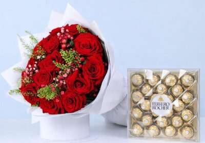 Red roses with delicate fillers in a white wrap, with a Ferrero Rocher box.