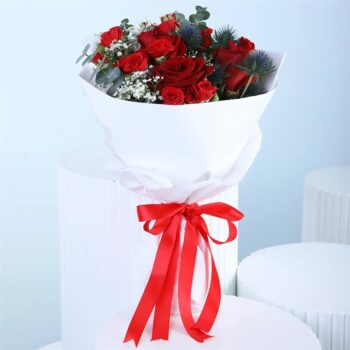 Mixed red bouquet with red roses, red spray roses, eucalyptus, and gypsophila in white wrapping style, finished with a ribbon.