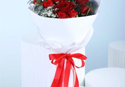 Mixed red bouquet with red roses, red spray roses, eucalyptus, and gypsophila in white wrapping style, finished with a ribbon.