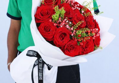 red roses with fillers in white wrap finished with a ribbon