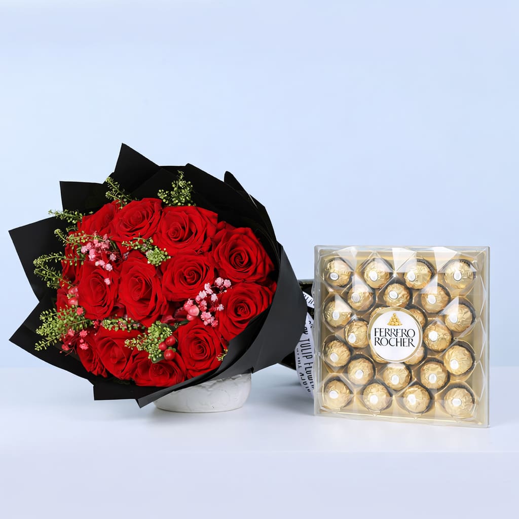 Red roses with filler flowers and green foliage in black wrapping, paired with Ferrero Rocher chocolates.